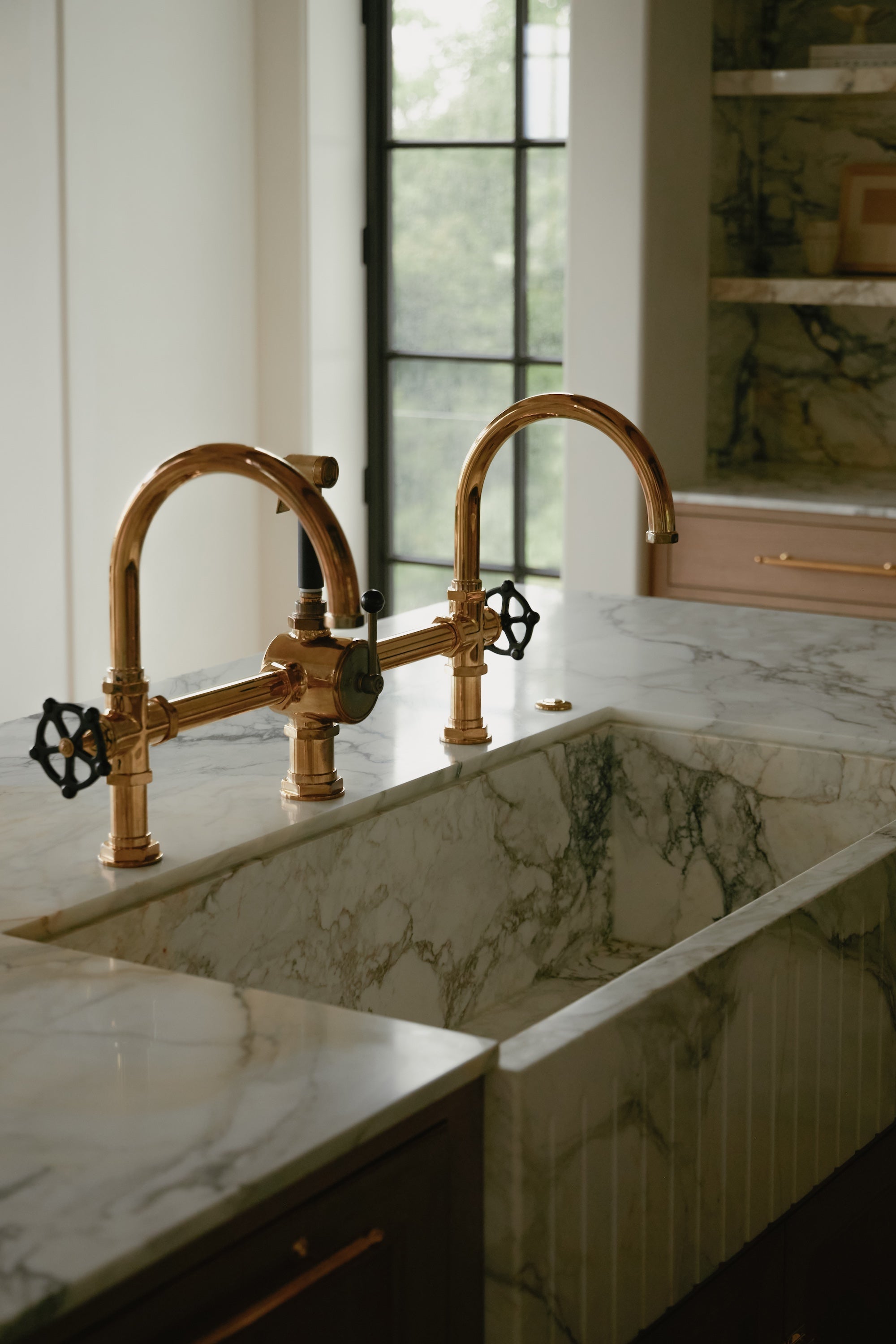 A close-up image of a marble sink with brass faucets.