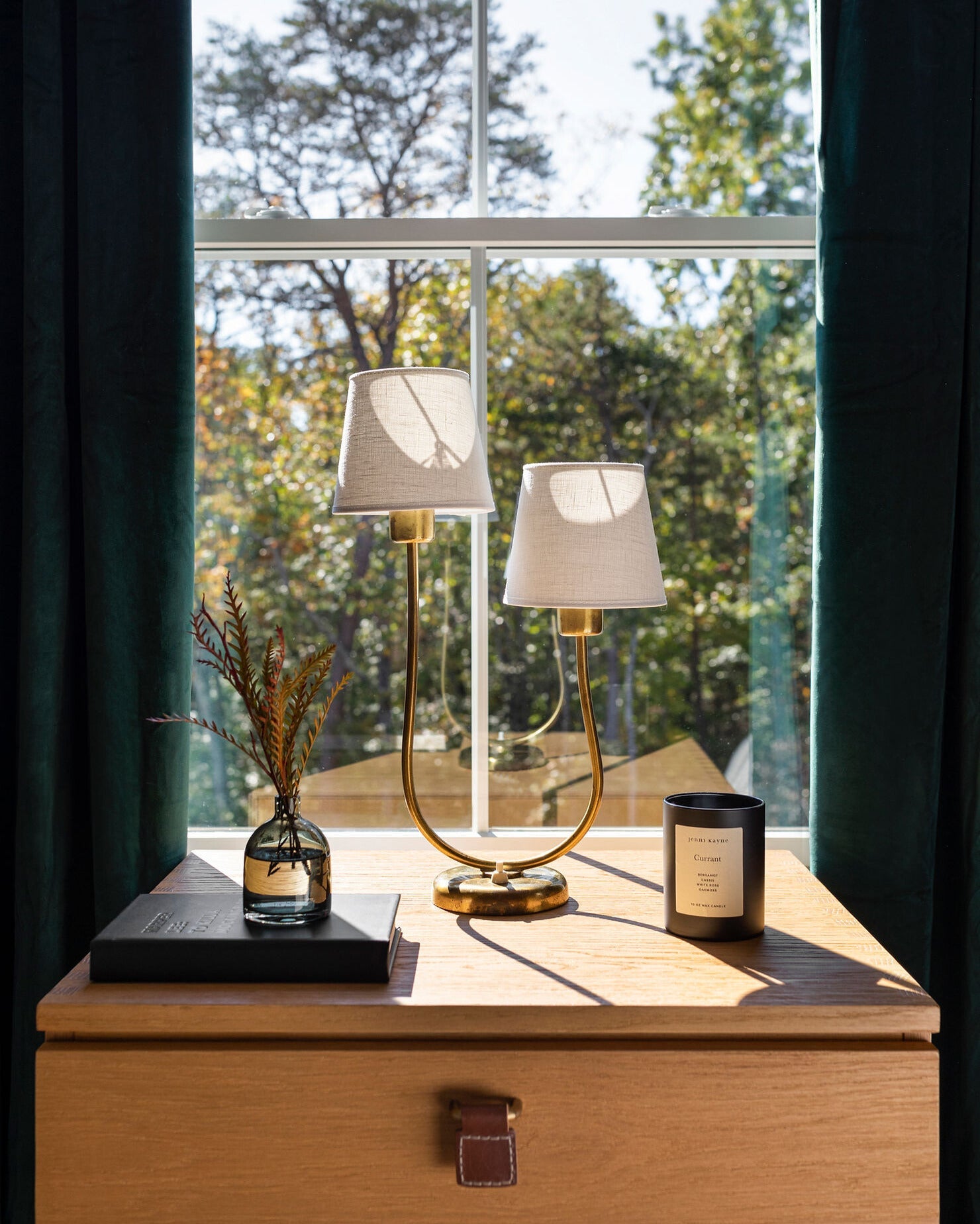 An image of a wooden nightstand with a brass lamp.